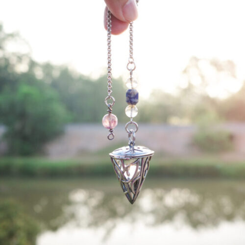 Foretelling the future with crystal pendulum. holding and using quartz crystal pendulum and using it, nature background.
